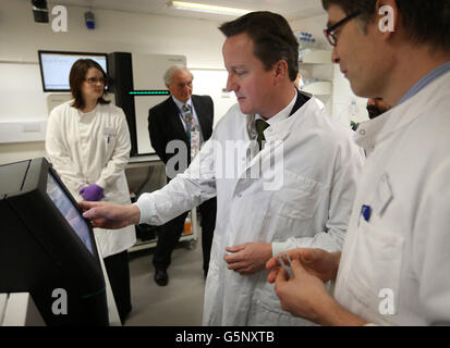 Prime Minister David Cameron (second right) stands with Dr James Hadfield (right) as he uses a personal genome sequencing machine during a visit to the Cancer Research UK Cambridge Research Institute in Cambridge, England. Stock Photo