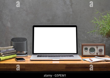blank screen laptop on wooden worktable concrete wall background Stock Photo