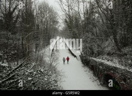 Joggers in the snow along the Parkland Walk nature reserve trail, in north London. Stock Photo
