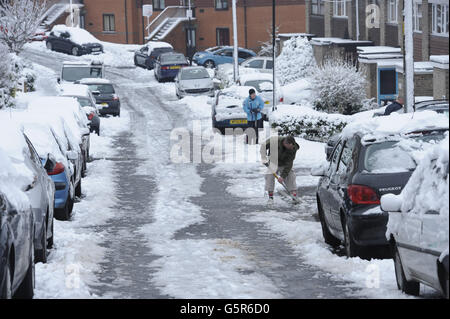 Residents help to clear snow and ice from a residential cul-de-sac at the top of a steep hill in Brislington, Bristol. Stock Photo