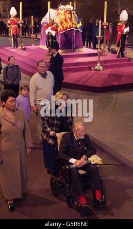 Veteran actor Sir John Mills (in wheelchair) pays his respect as he passes the coffin of Queen Elizabeth, the Queen Mother which lies in state in Westminster Hall, before her funeral at Westminster Abbey. Stock Photo