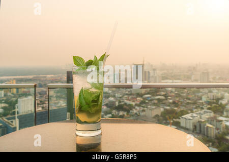 Mojito cocktail on table in rooftop bar. Rooftop bar in Bangkok, Thailand. Rooftop bar with sunset. Stock Photo