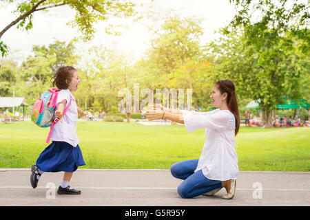 Family, Kids and Mother - Kids student running into mother's hands to hug her. Family having fun in the park. Kids is happy to m Stock Photo