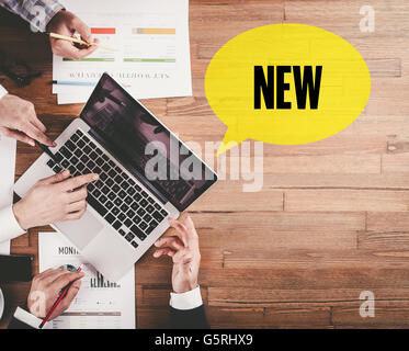 BUSINESS TEAM WORKING IN OFFICE WITH NEW SPEECH BUBBLE ON DESK Stock Photo