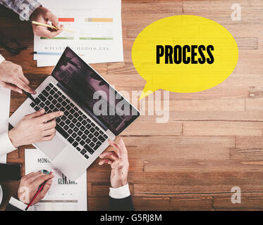 BUSINESS TEAM WORKING IN OFFICE WITH PROCESS SPEECH BUBBLE ON DESK Stock Photo