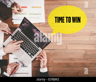 BUSINESS TEAM WORKING IN OFFICE WITH TIME TO WIN SPEECH BUBBLE ON DESK Stock Photo