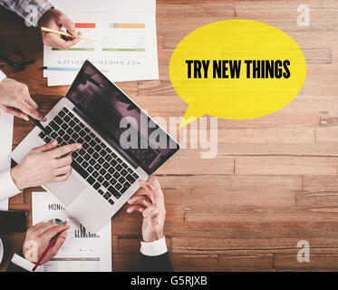 BUSINESS TEAM WORKING IN OFFICE WITH TRY NEW THINGS SPEECH BUBBLE ON DESK Stock Photo