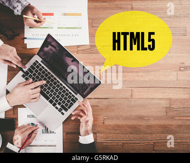BUSINESS TEAM WORKING IN OFFICE WITH HTML5 SPEECH BUBBLE ON DESK Stock Photo