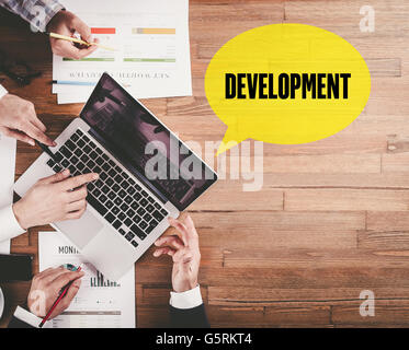 BUSINESS TEAM WORKING IN OFFICE WITH DEVELOPMENT SPEECH BUBBLE ON DESK Stock Photo