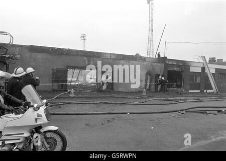 Fireman hose down the charred remains on the main stand at Bradford City's Valley Parade stadium, where 56 people died and 265 were injured as a fire swept the packed stand just before half-time of the game against Lincoln City. Stock Photo