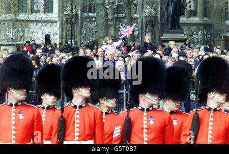 Grenadier Guardsmen and members of the public look on as the coffin of the Queen Mother passes on its way to Westminster Abbey in central London. Royal dignitaries and politicians from around the world have gathered at Westminster Abbey to pay their respects to the Queen Mother. *.., who died on March 30, 2002, aged 101. She will be interred at St George's Chapel in Windsor next to her late husband King George VI. Stock Photo