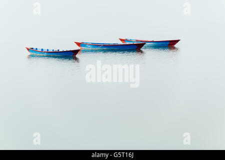 Three blue small boats on Phewa Lake in Pokhara, Nepal Stock Photo