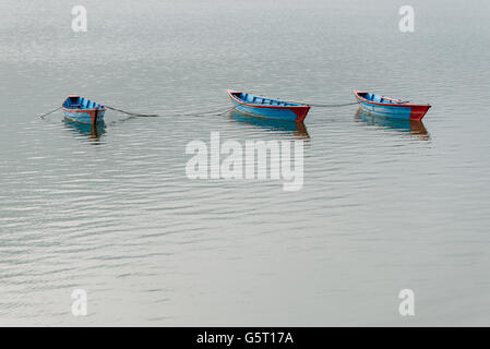 Three blue small boats on Phewa Lake in Pokhara, Nepal Stock Photo