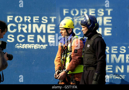 A Greenpeace protestor dressed as a workman is stopped and photographed by a police photographer before being led away by a riot policeman from outside the Cabinet Rooms in Whitehall, London, following a protest inside the Rooms. *The activists are displaying a door which was awaiting installation inside the Rooms which they say is made out of a tropical hardwood obtained from ancient forests from the Cameroon in central Africa. British Prime Minister Tony Blair has previously pledged to lead international action to protect the world's remaining ancient forests. Stock Photo