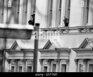 PC Trevor Lock, the policeman who is one of the three Britons caught up in the siege drama at the Iranian Embassy in London, speaking to police negotiators from a window at the embassy as a man of Middle Eastern appearance buries his head in his hands. Stock Photo