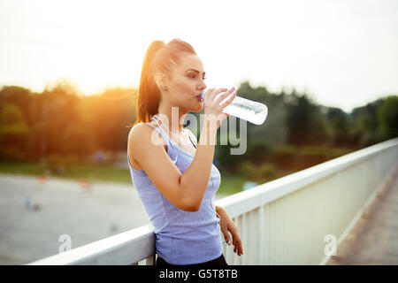 Woman drinking water after running to stay hydrated Stock Photo