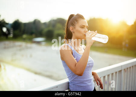 Woman drinking water after running to stay hydrated Stock Photo