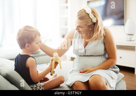 Beautiful mother cuddling child while earing a banana Stock Photo