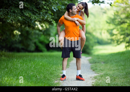Man carrying woman piggyback after jogging is done Stock Photo
