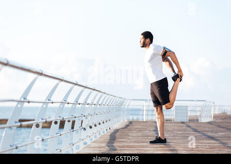 Full length of attractive african american sportsman standing and stretching legs Stock Photo