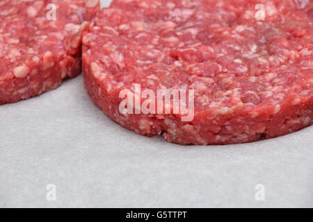 Raw red meat burgers for hamburgers of minced ground beef or pork on white parchment paper ready for cooking Stock Photo