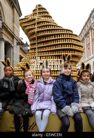 A group of young girls sit in front of a giant bunny made of hundreds of small chocolate bunnies, as part of the giant Easter Egg hunt, in which 100 large hand-painted eggs will be hidden in cities throughout the country from today until the 1st April, as part of the Lindt Big Egg hunt in support of the Action for Children Charity, in Covent Garden in central London. Stock Photo