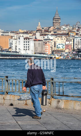 Tea vendor at Eminonu with view across the Golden Horn and the Galata tower in the background. Istanbul, Turkey. Stock Photo