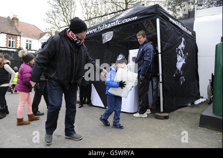 Young Fulham fans receive their foam fingers and goody bags outside the Putney End Stock Photo