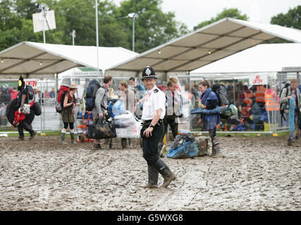 A police officer patrols a camp site as festivalgoers arrive for the Glastonbury festival at the Worthy Farm site, Somerset, where heavy rain over a prolonged period has caused isolated flooding and muddy fields. Stock Photo