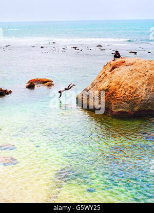 Boys swimming and jumping to the ocean from the rock. Sri Lanka