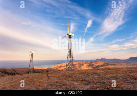 Industrial landscape with wind turbine generating electricity in mountains at sunset. Stock Photo