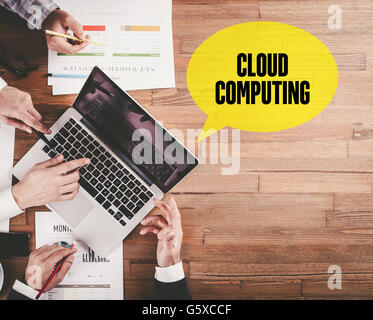 BUSINESS TEAM WORKING IN OFFICE WITH CLOUD COMPUTING SPEECH BUBBLE ON DESK Stock Photo