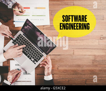 BUSINESS TEAM WORKING IN OFFICE WITH SOFTWARE ENGINEERING SPEECH BUBBLE ON DESK Stock Photo