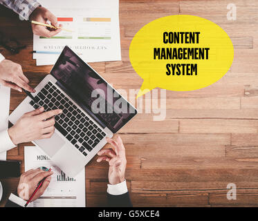 BUSINESS TEAM WORKING IN OFFICE WITH CONTENT MANAGEMENT SYSTEM SPEECH BUBBLE ON DESK Stock Photo