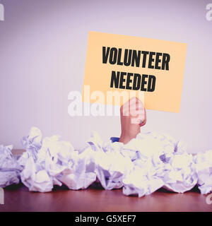 HAND HOLDING YELLOW PAPER WITH VOLUNTEER NEEDEDCONCEPT Stock Photo