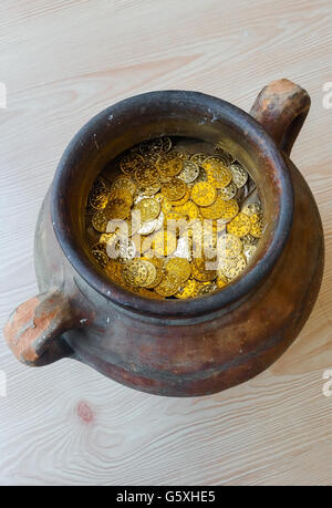 Fake gold and silver coins in earthenware jar Stock Photo