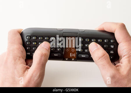 Man's hands holding a remote control keypad Stock Photo