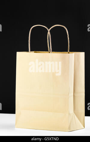 Close up of plain brown shopping bag with twisted paper handles on a white and black background. Stock Photo