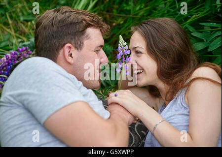 Young happy beautiful couple man and woman lying outdoors on green grass Stock Photo