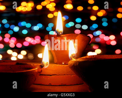 Traditional lamps lit in front of colorful lighting, during Diwali festival in India. Stock Photo