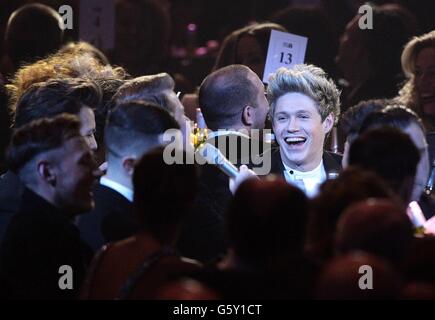 Niall Horan (right) laughs as One Direction are interviewed by James Corden during the 2013 Brit Awards at the O2 Arena, London. Stock Photo