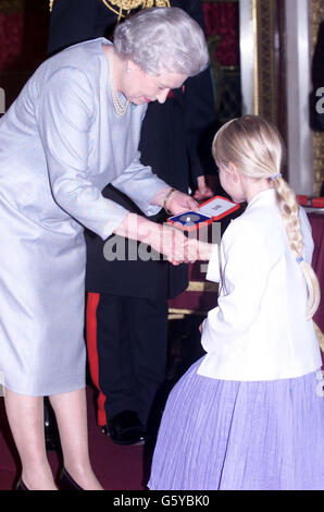 Queen Elizabeth II presenting a silver medal to Louise Shaw, aged 8, from St Martins Church of England primary school in Dorking, Surrey, who was a winner in the Queen's Golden Jubliee poetry competition. * Some 4,000 children from England, Wales, Scotland and Northern Ireland entered the competition and the winners were invited to Buckingham palace for the presentation. Stock Photo