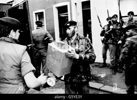 Men of the 1st Battalion Welsh Guards carry a made -up bomb from the terrace house 'bomb factory' they uncovered during a dawn swoop on Keegan Street. Stock Photo