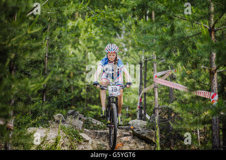 young girl cyclist riding his bike on stones in spruce forest Stock Photo