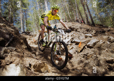 male athlete cyclist rides down mountain on stones Stock Photo