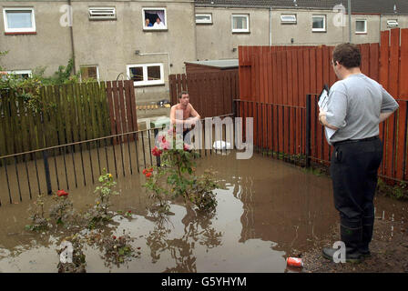 Householder Billy Craig (left) speaks to an official outside his house on Cockenzie Street in the Shettleston area of Glasgow, as he views the damage caused by flooding. Stock Photo