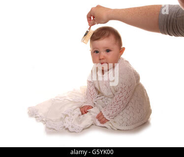 Mother combing babys girls hair before christening cutout Stock Photo