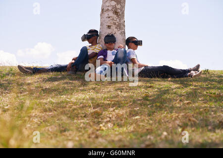 Youth culture, multiethnic group of male teens playing with VR outdoors in park. Stock Photo