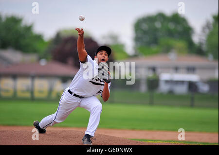 Right-handed pitcher releasing a pitch to a waiting hitter during a high school baseball game. Stock Photo