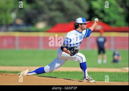 Left-handed pitcher delivering a pitch to a waiting hitter during a high school baseball game. USA. Stock Photo